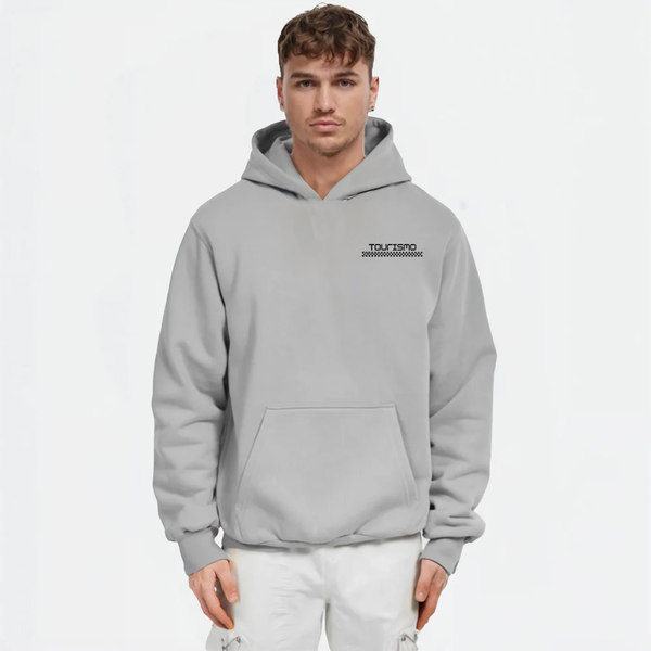 Homme portant un hoodie gris clair TOURISMO avec pantalon blanc, sur fond blanc
