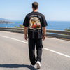 Homme portant le t-shirt noir Tourismo Club Ferrari F40 sur une route côtière face à la mer