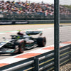 Homme de dos en t-shirt Kimi Antonelli au bord de la piste, une monoplace passe en vitesse derrière lui