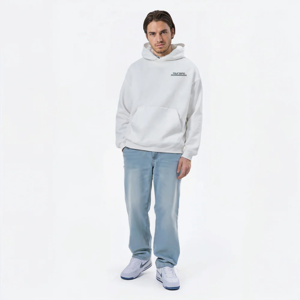 Hoodie blanc logo TOURISMO, homme en jean clair avec baskets blanches sur fond blanc