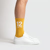 Chaussettes Ayrton Senna 12, saison 1988 jaune, portées de profil avec des sneakers blanches